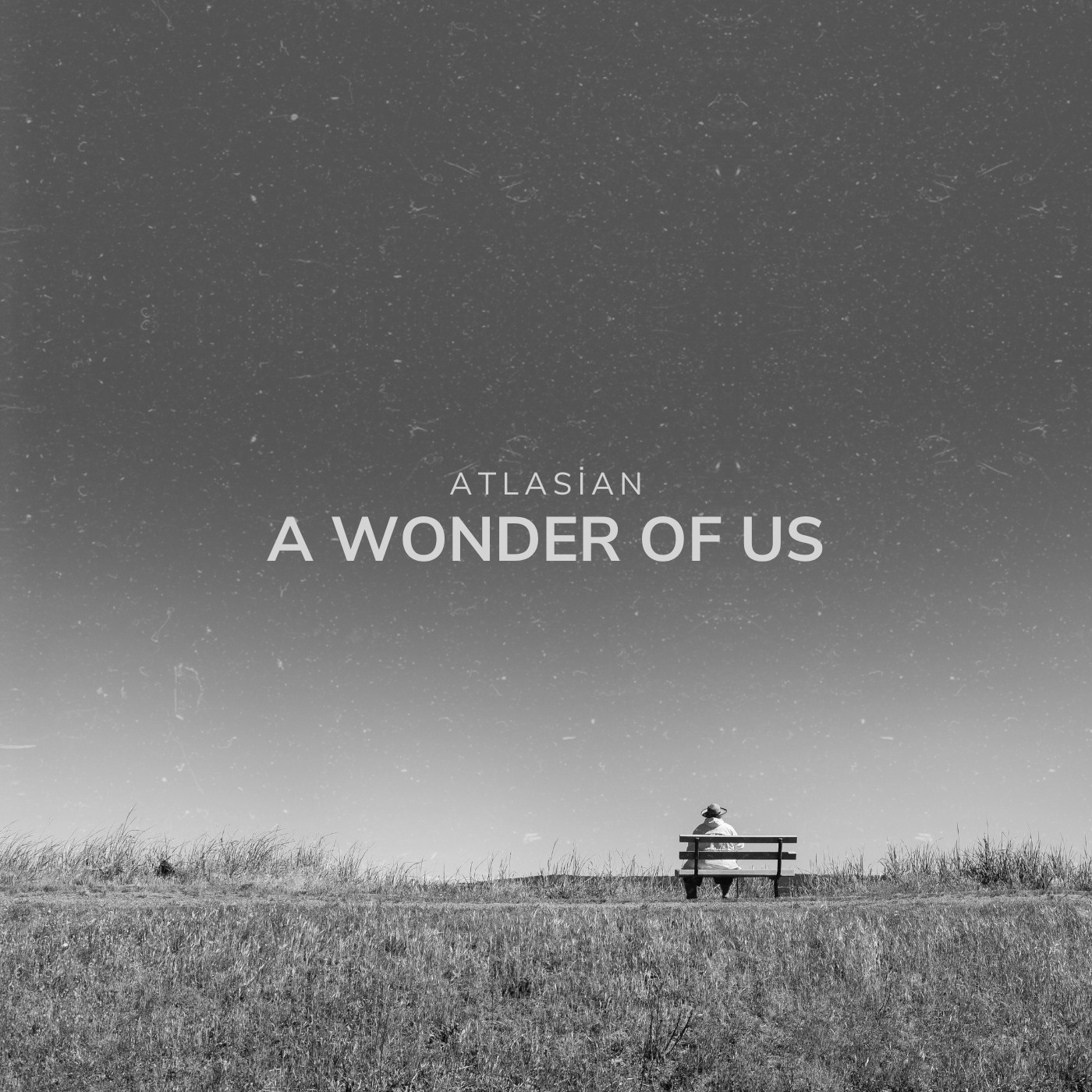 Black and white cover showing a lone person sitting on a bench in an open field beneath a vast sky